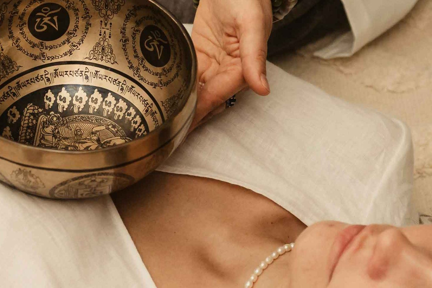 Klient w trakcie terapeutycznego masażu misami tybetańskimi położonymi na ciele MuzOna Iwona Chomiczewska